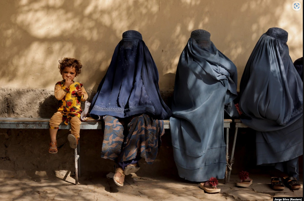 a_girl_sits_with_women_wearing_burqas_outside_a_hospital_in_kabul_on_october_5
