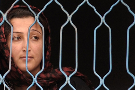 An Afghan prisoner lookd out from a fenced window at the Female Detention Centre in Kabul