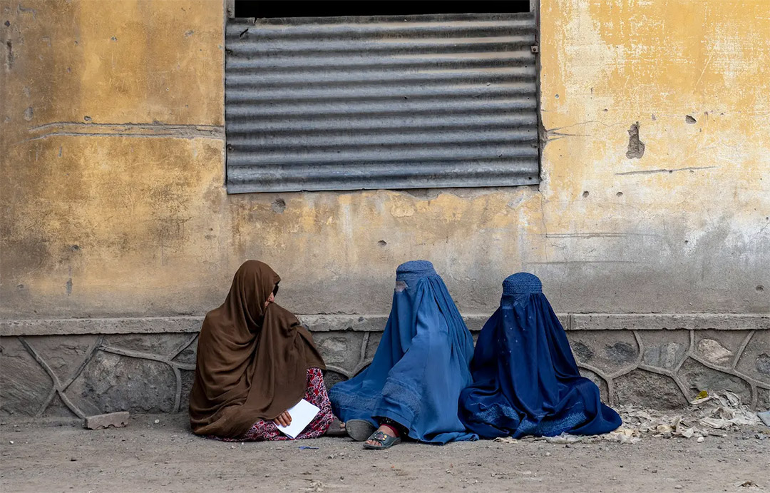 Afghan women wait to receive food rations
