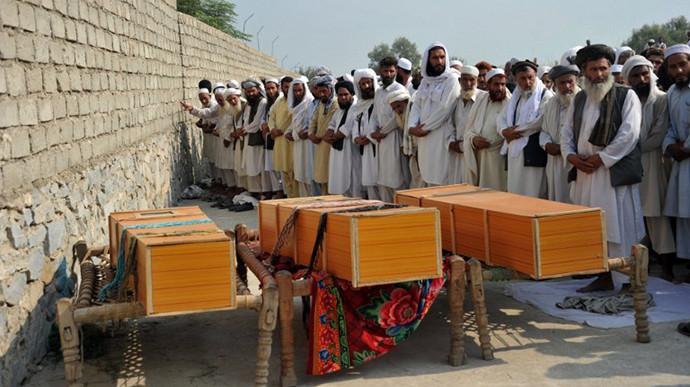 Afghan men pray alongside the coffins of civilians, allegedly killed in a NATO air strike, on the outskirts of Jalalabad in Nangarhar province