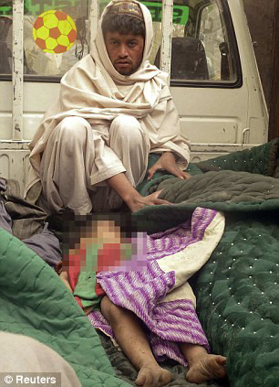 A man sits in a truck bed keeping watch over the body of a young boy