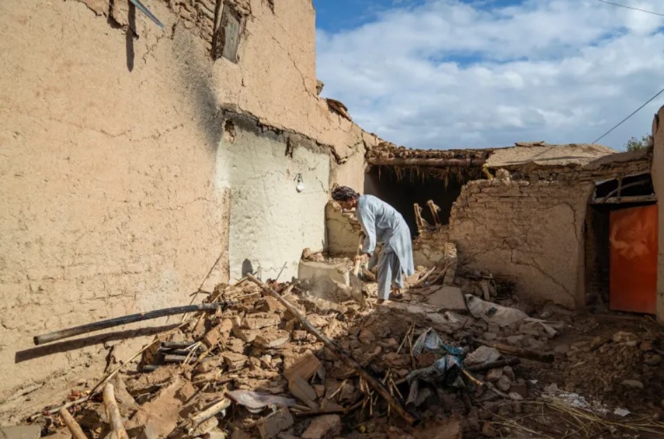 An Afghan man clears rubble from the courtyard of his damaged house